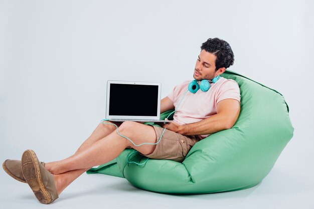 Man on sofa qui présente un ordinateur portable