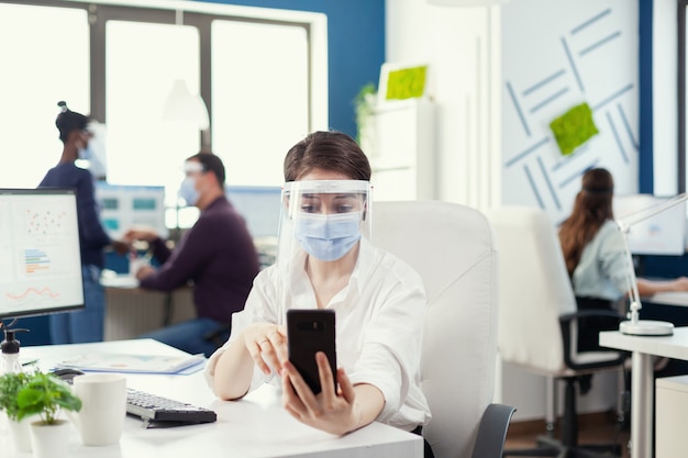 Manager utilisant un smartphone pour une conférence en ligne portant un masque facial contre covid-19 par mesure de sécurité