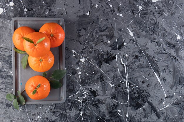 Mandarine fraîche sur une assiette en bois, sur la table mixte.