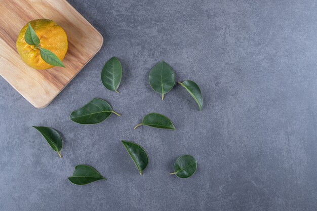 Mandarine fraîche sur planche de bois et feuilles.