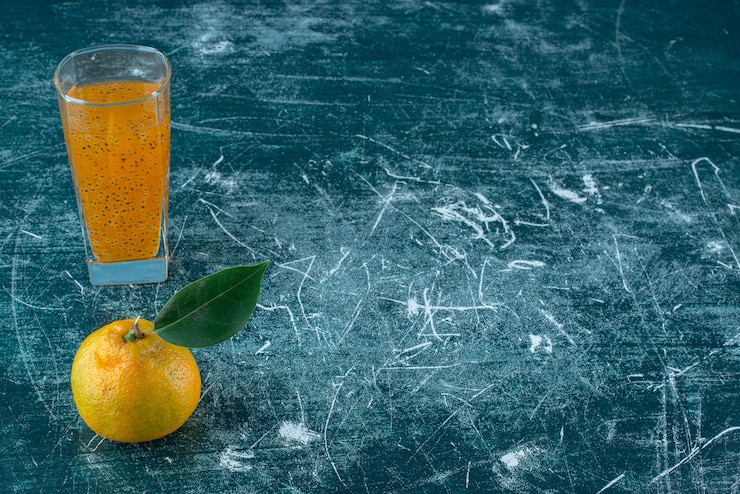 Photo gratuit mandarine et un verre de jus sur le fond bleu. photo de haute qualité