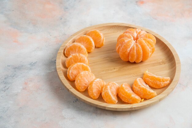 Mandarines de clémentine pelées sur plaque en bois