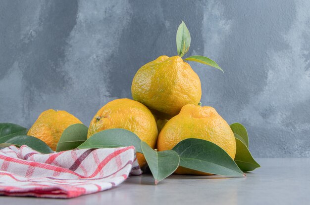 Des mandarines empilées sur une serviette sur du marbre.