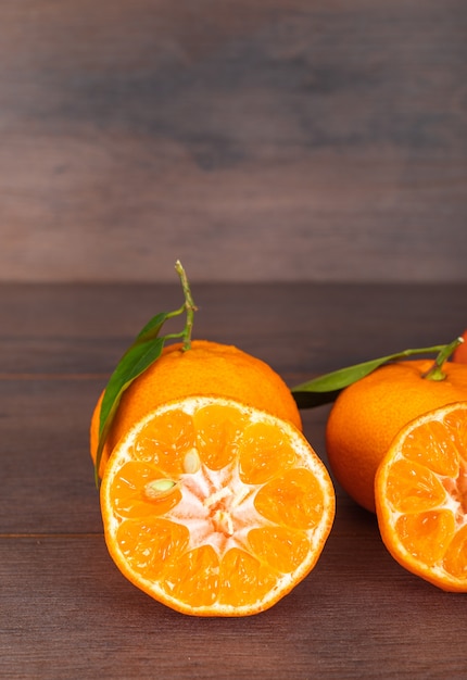 Photo gratuite mandarines avec des feuilles sur une surface brune