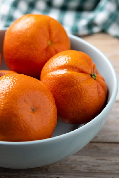 Photo gratuite mandarines fraîches dans un bol sur une table en bois