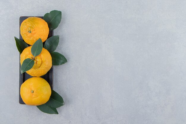 Mandarines fraîches avec des feuilles sur plaque noire