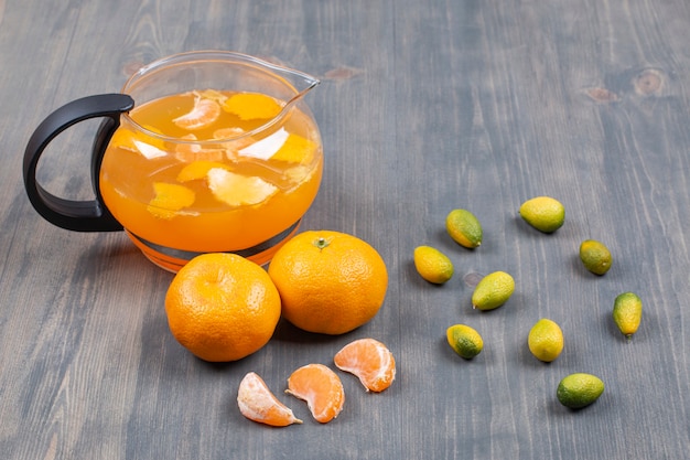 Mandarines fraîches et jus sur une surface en bois