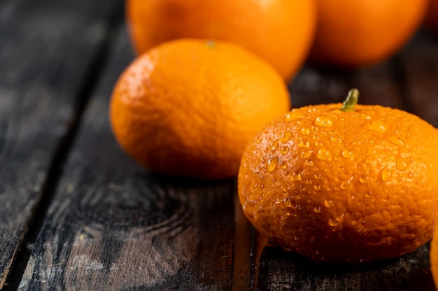 Mandarines avec des gouttes d'eau sur une table en bois