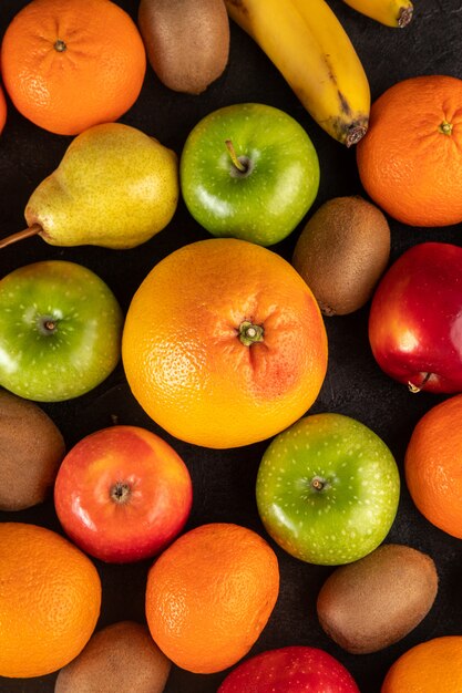 Mandarines et kiwis fruits de différentes couleurs comme les poires pommes vertes et les oranges sur fond gris