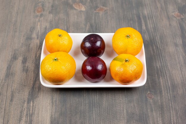 Mandarines sucrées aux prunes sur une table en bois. Photo de haute qualité