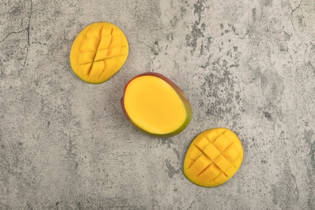 Mangue de fruits tropicaux en tranches avec des cubes sur une surface en marbre.