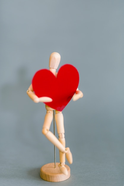 Mannequin en bois tenant coeur rouge
