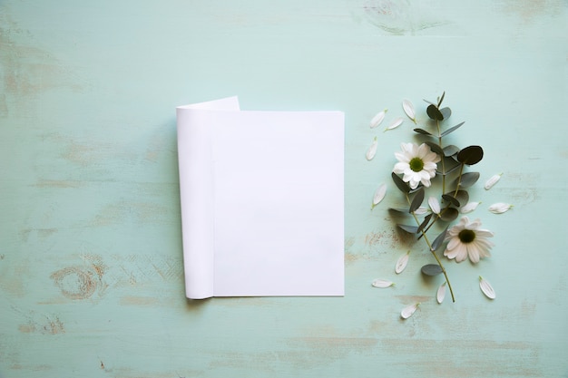 Photo gratuite maquette d'une feuille de papier à côté d'une fleur