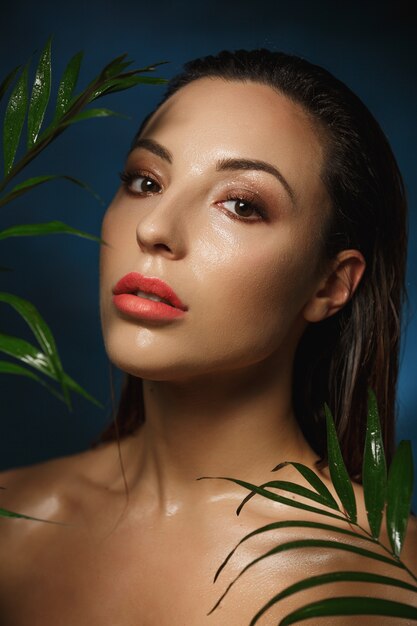 Maquillage humide. Style de photographie de mode. Femme nue dans les feuilles.