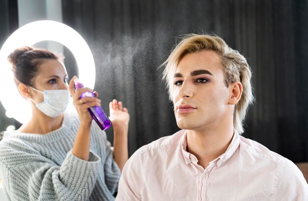 Maquillage masculin à l'aide de laque pour cheveux