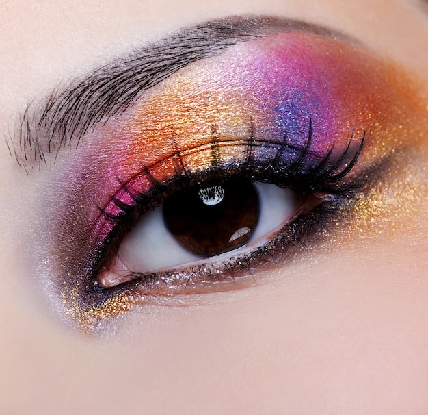 Maquillage multicolore lumineux sur l'oeil féminin - macro shoot
