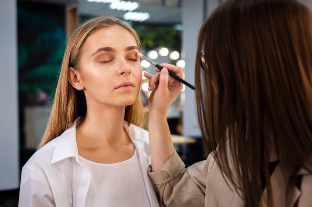 Maquilleuse appliquant un fard à paupières sur le visage avec un pinceau