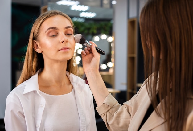 Maquilleuse appliquant la poudre sur le visage avec un pinceau