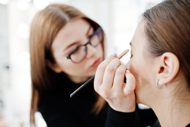 Maquilleuse travaille dans son salon de studio de beauté Visage Femme appliquant par un maître de maquillage professionnel Concept de club de beauté