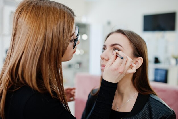 Maquilleuse travaille dans son salon de studio de beauté Visage Femme appliquant par un maître de maquillage professionnel Concept de club de beauté