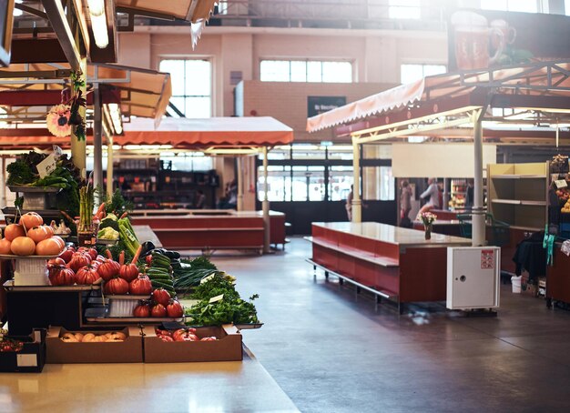 Marché aux légumes de saison avec une variété de produits agricoles sur les étagères et dans les caisses.