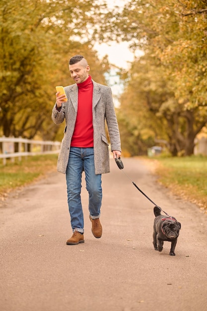 Marchez avec un ami. Homme marchant avec un chien dans un parc