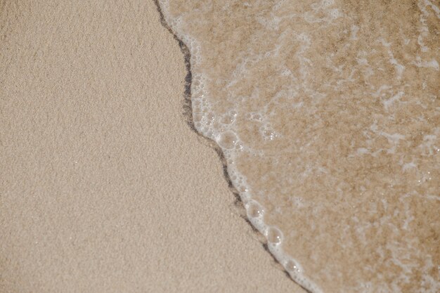 Marée avec des bulles coulant sur le sable