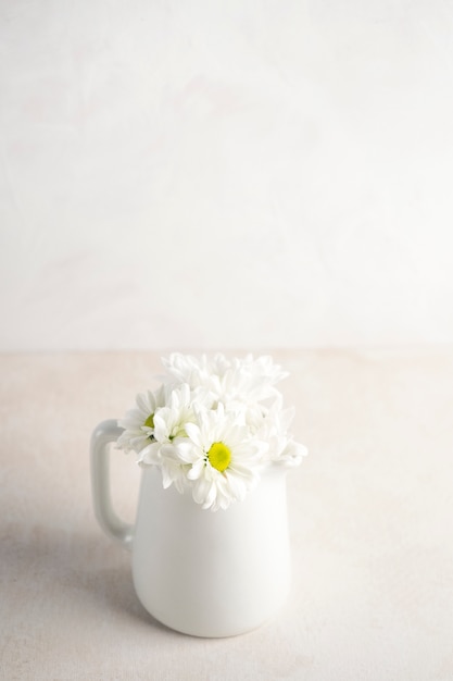 Marguerite de fleurs en pichet sur la table