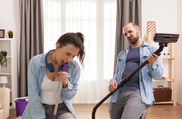 Mari et femme chantant ensemble tout en nettoyant l'appartement