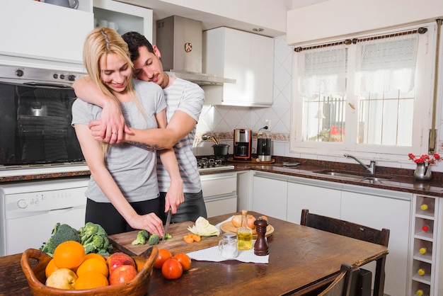 Mari s&#39;appuyant sur l&#39;épaule de sa femme coupant des légumes avec un couteau