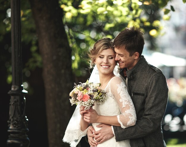 Le marié embrasse la mariée dans le parc