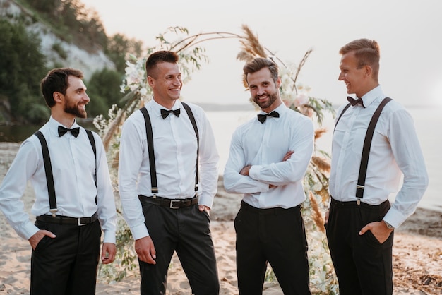 Photo gratuite marié et meilleurs hommes posant sur la plage