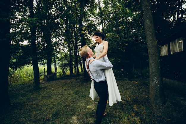 Le marié a soulevé la mariée dans ses bras dans le parc