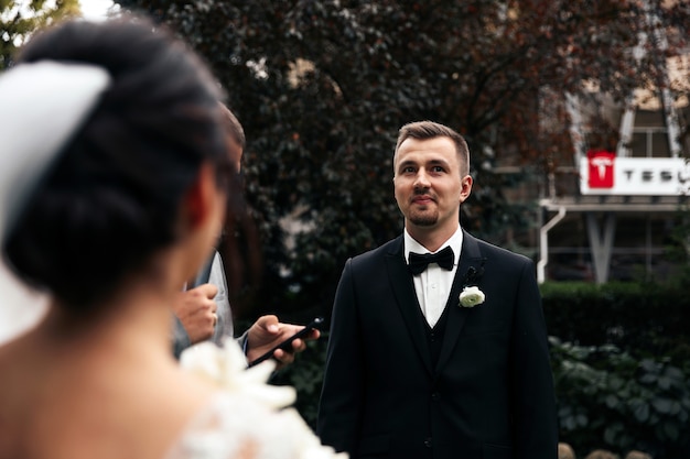 Le marié sourit à l'extérieur et vue arrière de la mariée