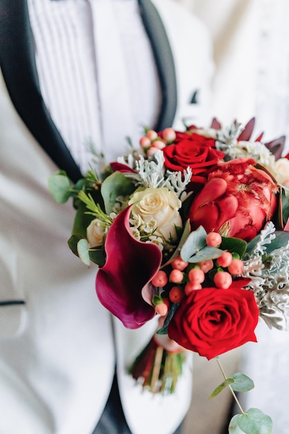 Photo gratuite le marié tient un bouquet de mariage dans ses mains