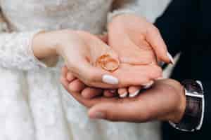 Photo gratuite le marié tient les mains de la mariée, où se trouvent deux alliances