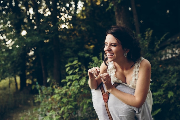 Le marié tient sa mariée dans ses bras quelque part dans la nature