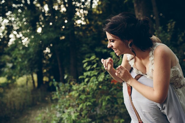 Le marié tient sa mariée dans ses bras quelque part dans la nature