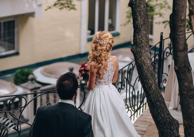 marié va à la mariée blonde près de la balustrade