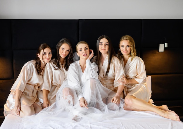 Mariée avec des amis filles posant au lit