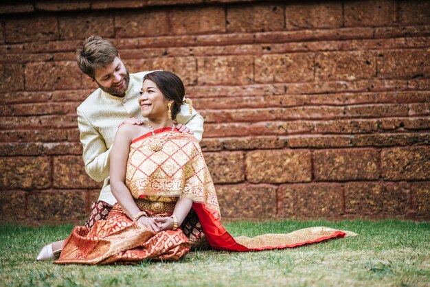 Mariée asiatique et marié caucasien ont du temps romantique avec la robe de la Thaïlande