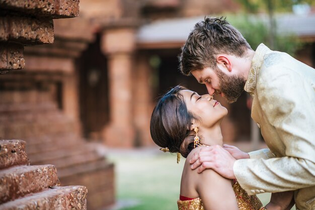 Mariée asiatique et marié caucasien ont du temps romantique avec la robe de la Thaïlande