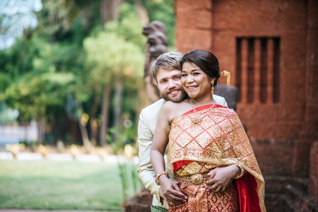 Mariée asiatique et marié caucasien ont du temps romantique avec la robe de la Thaïlande