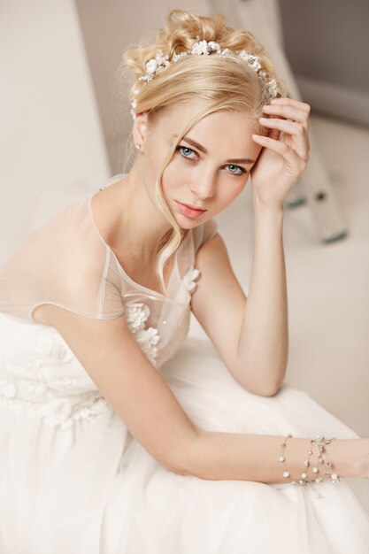 Mariée en belle robe debout à l'intérieur dans un intérieur de studio blanc comme à la maison.