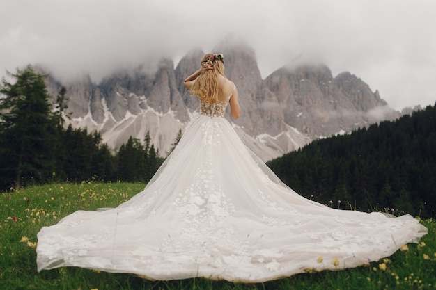 Photo gratuite la mariée dans une robe de luxe se dresse devant le magnifique paysage de montagne