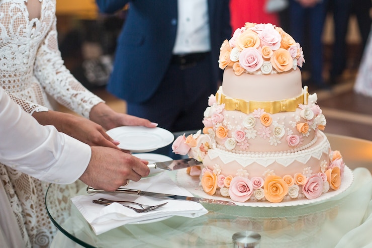 Photo gratuit mariée et le marié couper délicieux gâteau de mariage décoré avec beige