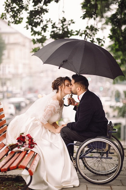 Mariée et le marié sur le fauteuil s&#39;asseoir s&#39;embrasser sur le banc dans le parc