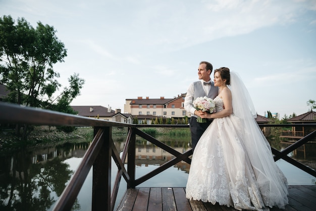 La mariée et le marié se tiennent sur le pont et détournent le regard