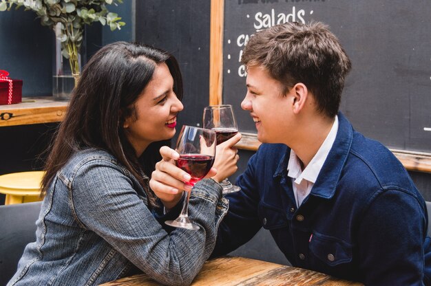 Mariée et le marié en souriant tout en croisant les bras avec des verres de vin