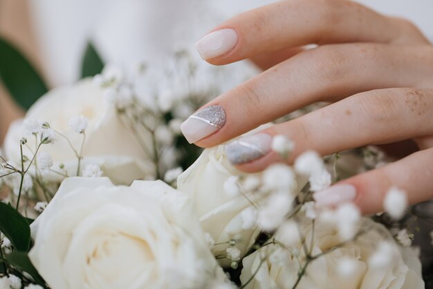 La mariée montre sa manucure sur un bouquet de mariage